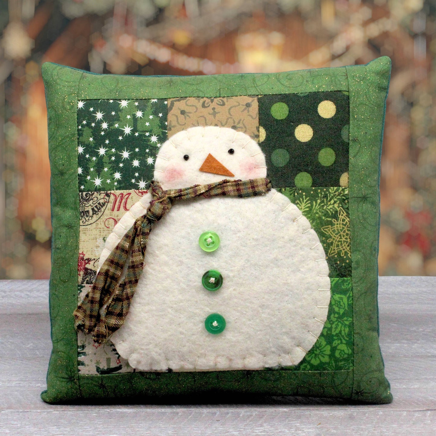 Country style handmade snowman pillow with a patched background.