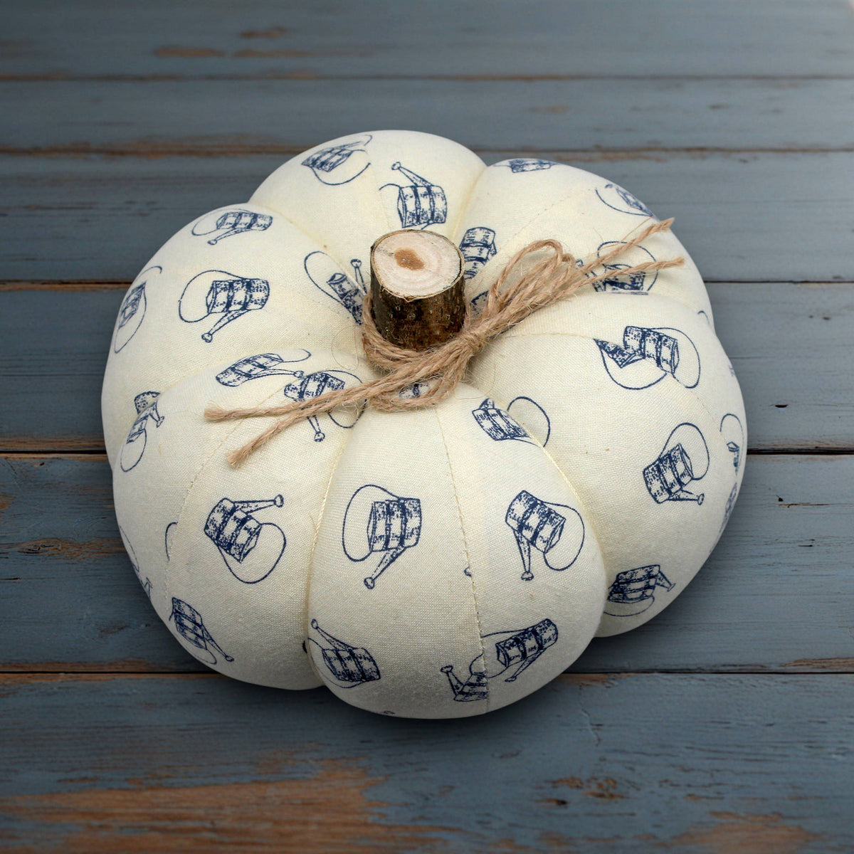 Fabric pumpkin with a watering can design on a white wooden surface