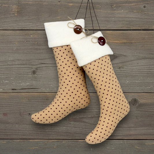Pair of handmade primitive Christmas stocking ornaments with tiny burgundy stars on a tan background