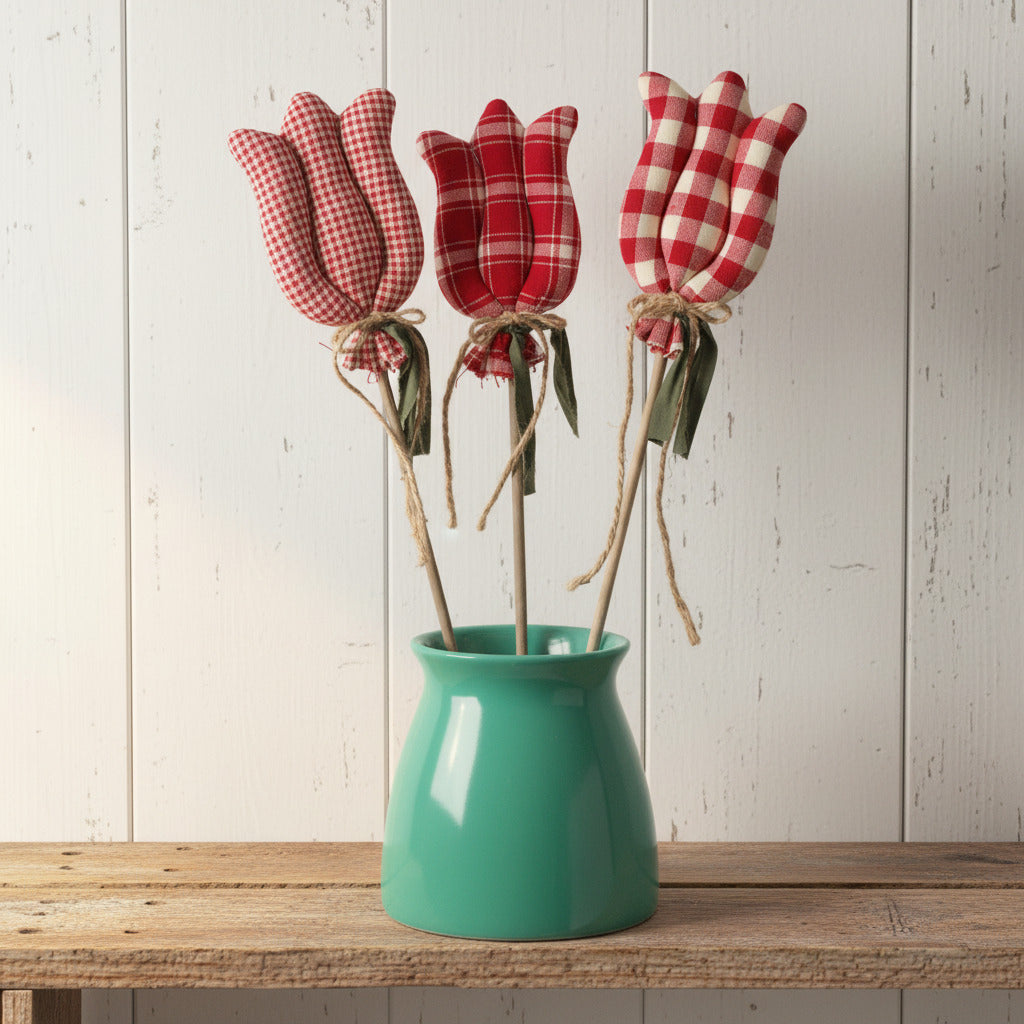 Three red and white checkered tulips in a green vase on a light gray background