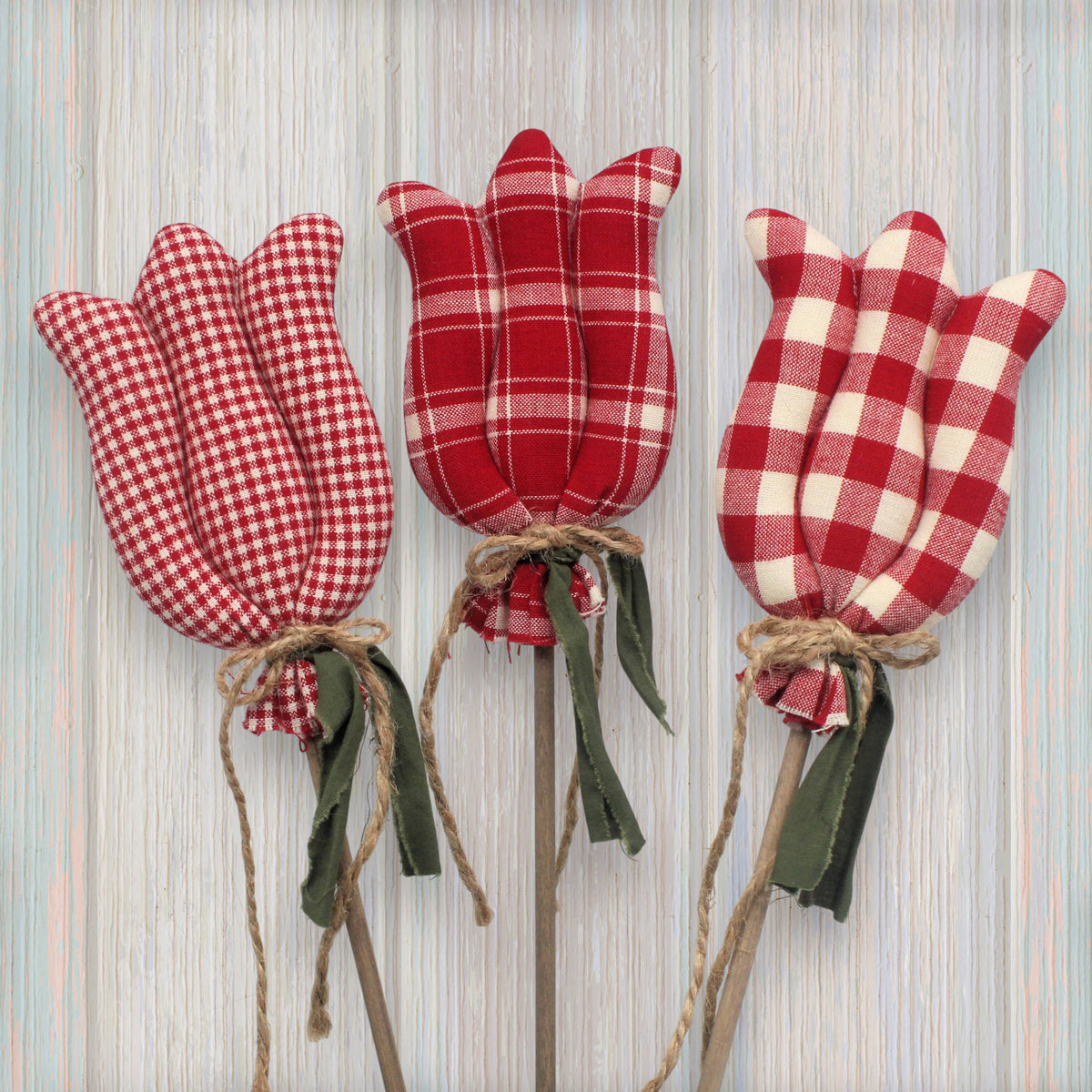 Three red and white checkered tulip-shaped decorations on a wooden background