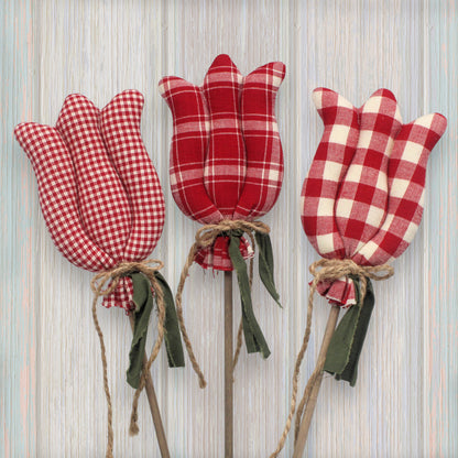 Three red and white checkered tulip-shaped decorations on a wooden background