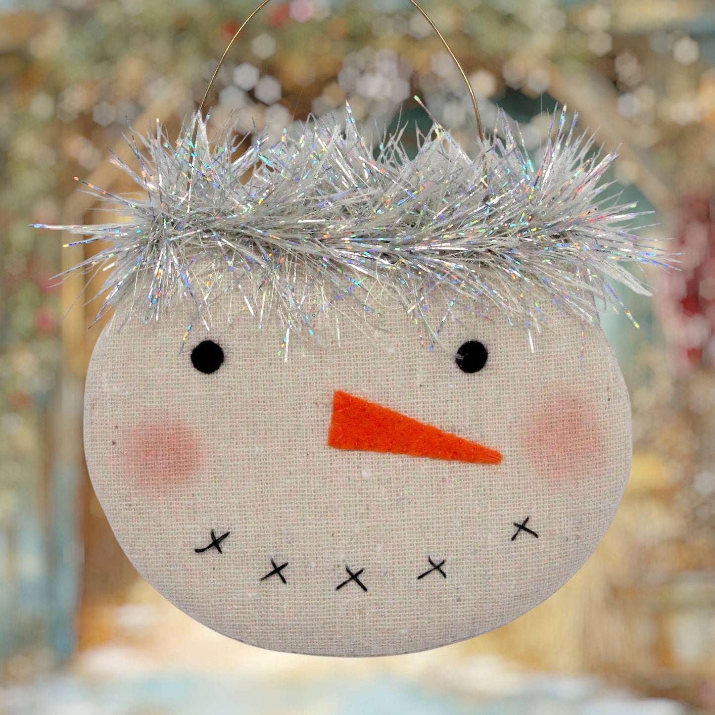 Country primitive snowman face ornament with a sparkly silver tinsel trim around the top.
