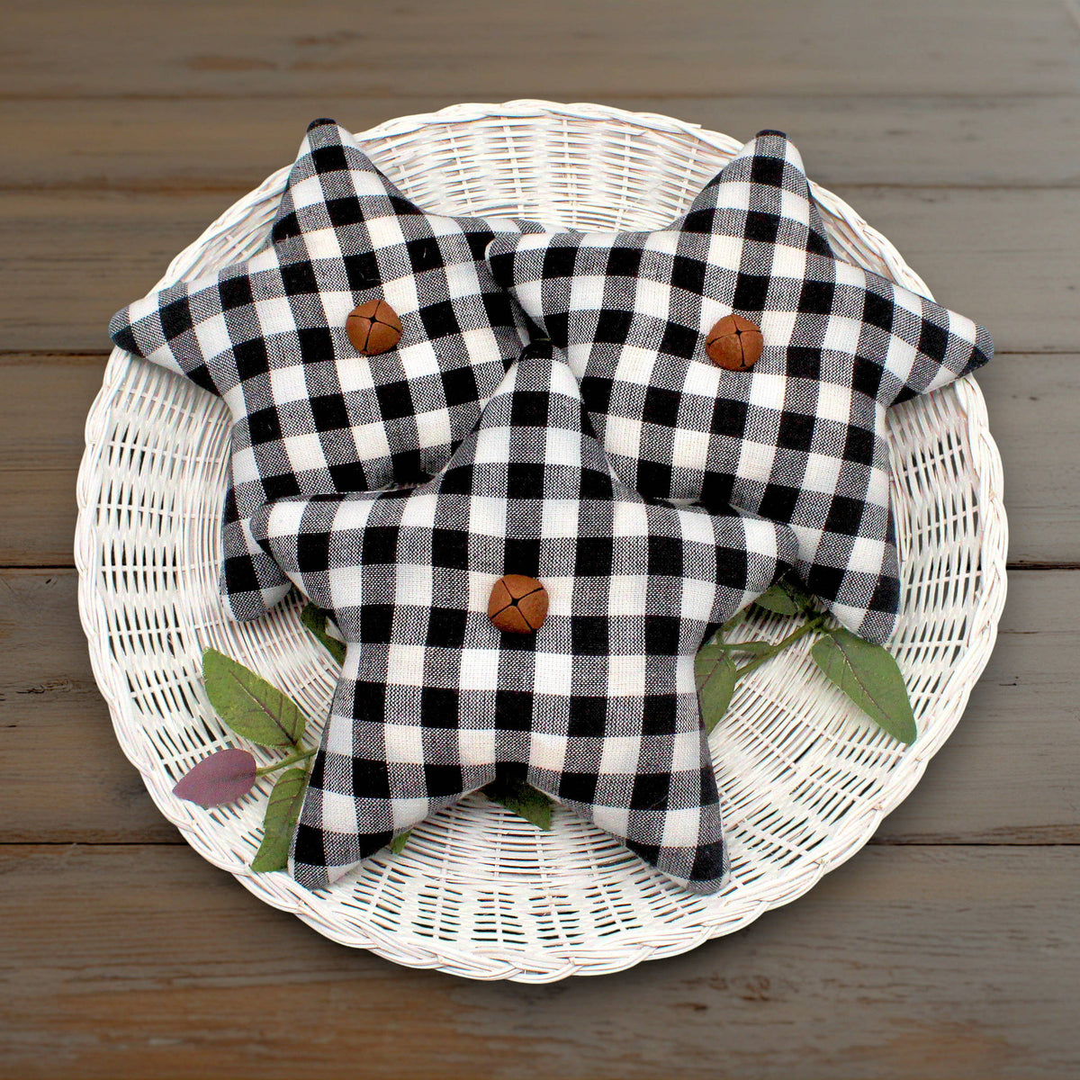 Set of three homespun fabric stars in a weave of black and white with rusty bells stitched to the centers