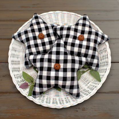 Set of three homespun fabric stars in a weave of black and white with rusty bells stitched to the centers