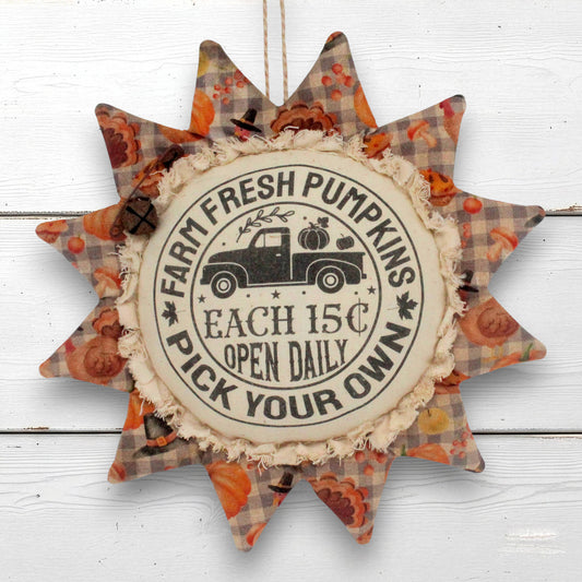 A sunflower ornament autumn hanging ornament with a central circular sign reading 'Farm Fresh Pumpkins Each 15c Open Daily Pick Your Own' and a vintage truck illustration, surrounded by patterned star points in orange, brown, and beige plaid.