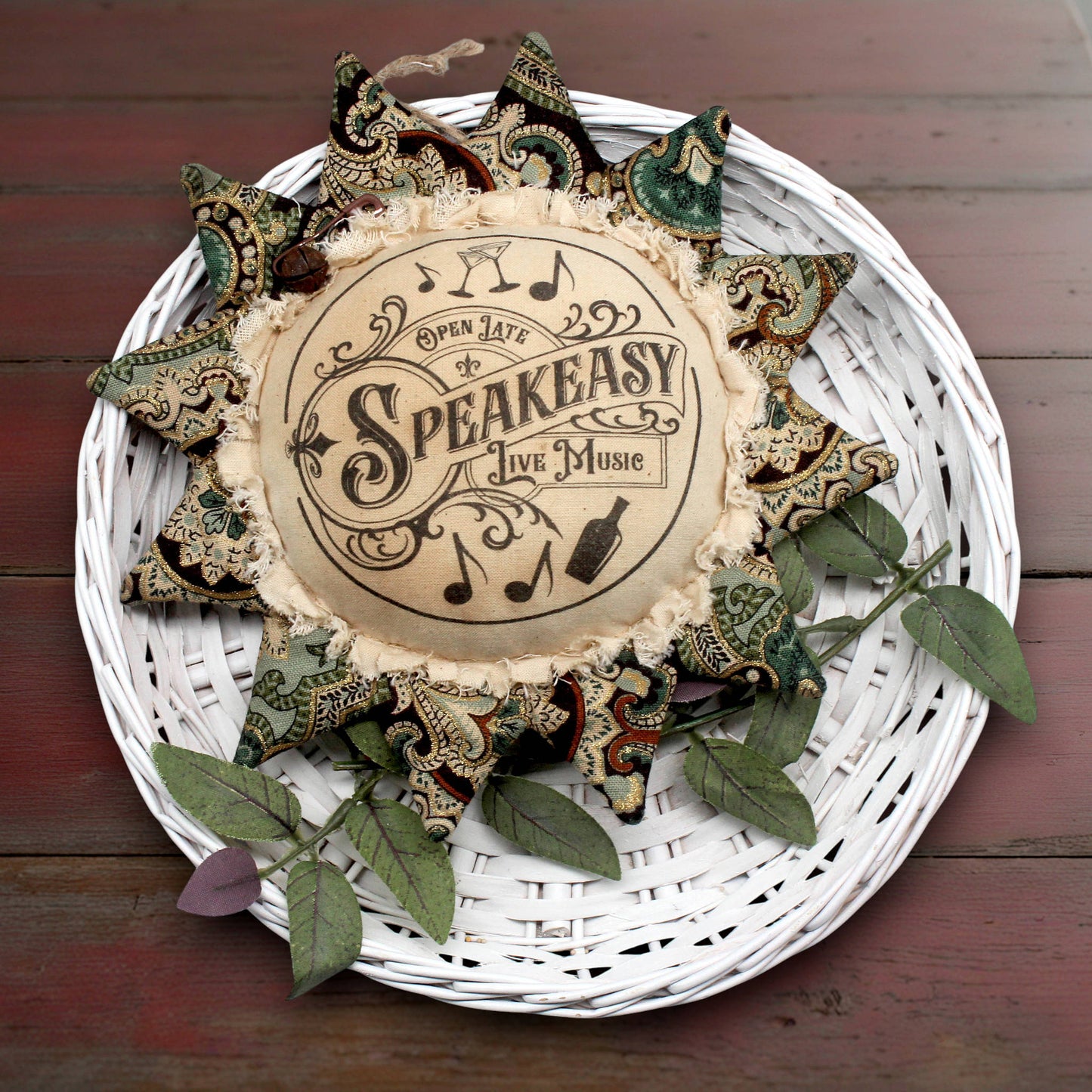 Decorative sunflower ornament with 'Speakeasy' text on a white woven plate with decorative elements.