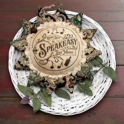 Decorative sunflower ornament with 'Speakeasy' text on a white woven plate with decorative elements.