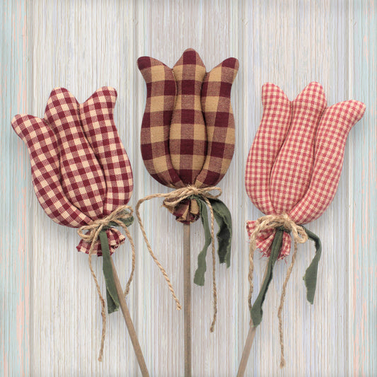 Three checkered tulip decorations on sticks against a striped background