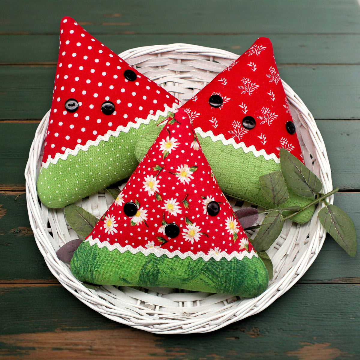 set of three primitive watermelon slice bowl fillers sewn from coordinating red print fabrics and trimmed with white rick rack and black buttons
