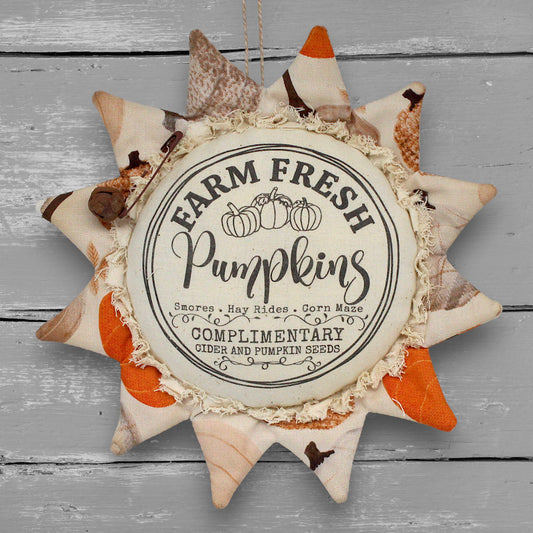 Primitive handmade fabric sunflower ornament with a printed center that advertises for farm fresh pumpkins
