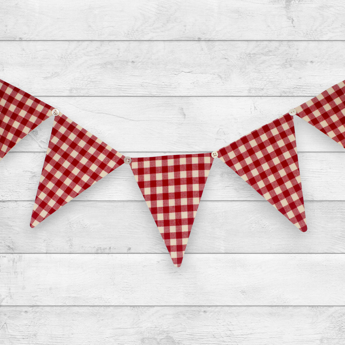 Red and cream gingham bunting banner with triangular flags hanging against a white wood plank background.