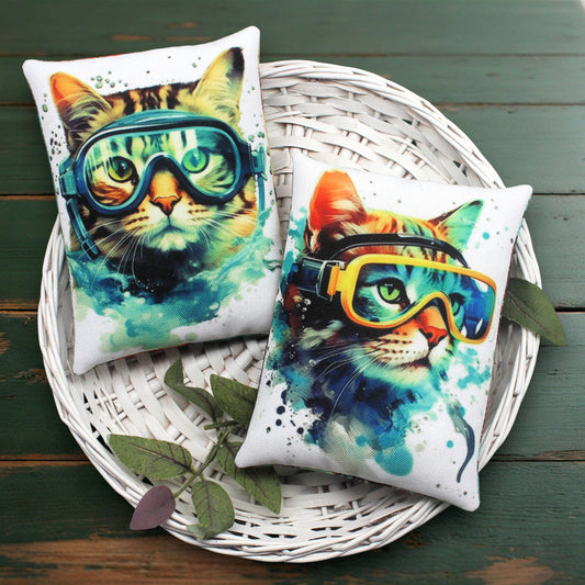 Two colorful cat pillows with goggles on a white wicker tray.