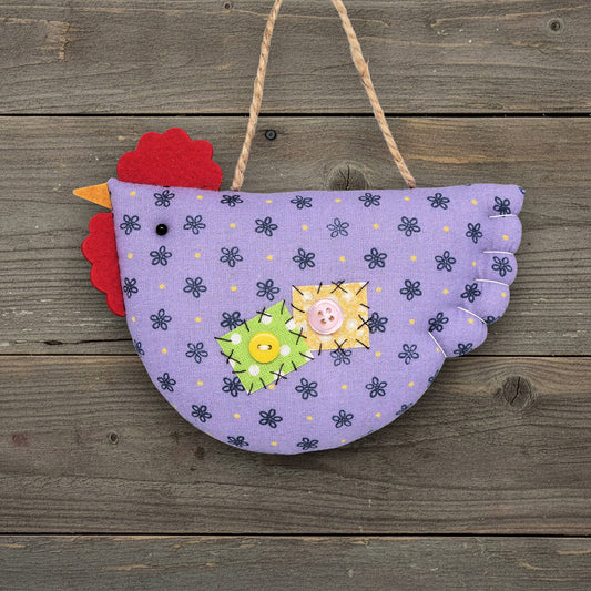 Decorative chicken ornament with a purple body and red comb on a wooden background