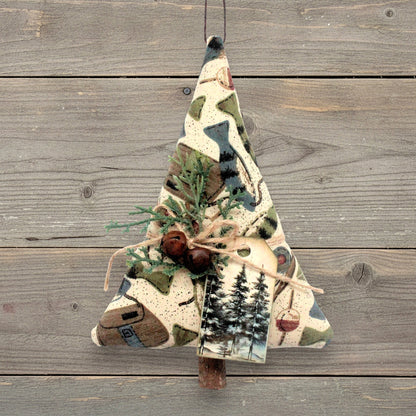 Handmade fabric tree-shaped Christmas ornament with fish and fishing gear on a tan background, decorated with rusty bells, pine and a tag