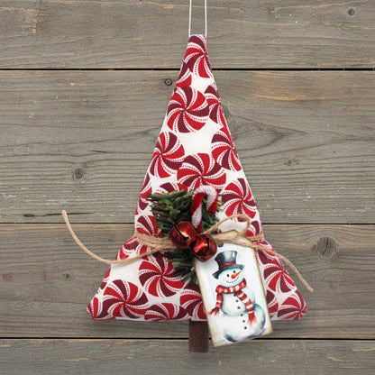 Handmade Christmas tree-shaped ornament with red peppermint candy wheels on a white background, red bells, pine and a snowman tag