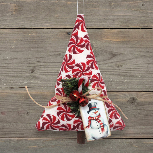 Handmade Christmas tree-shaped ornament with red peppermint candy wheels on a white background, red bells, pine and a snowman tag