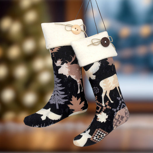 Two hanging Christmas stockings with a woodland deer and tree pattern on a black background, finished with cream fleexe cuffs and decorative buttons.