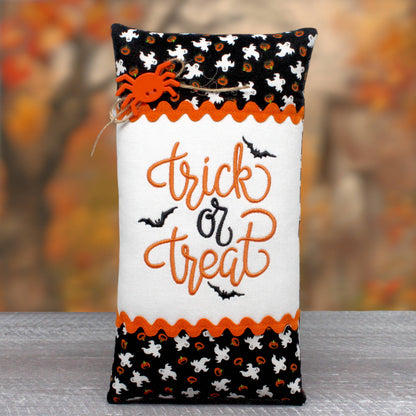 Elongated pillow tuck or bowl filler features a center panel that is embroidered with the words 'trick or treat.' The center panel is trimmed with rick rack and a print fabric with ghosts and jack-o-lanterns.