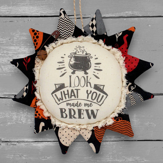 Handcrafted primitive sunflower ornament for Halloween with a printed center that reads "look what you made me brew."