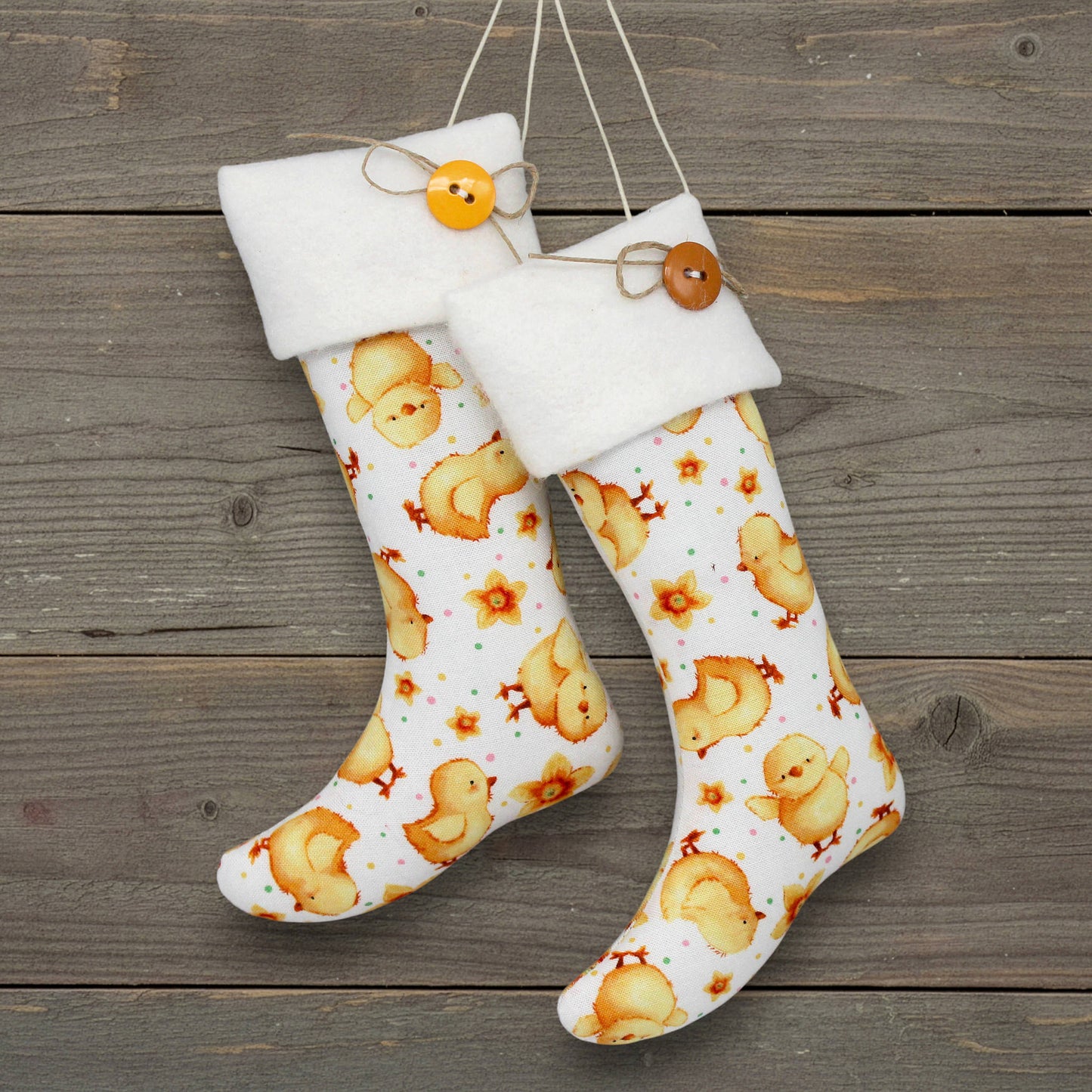 Pair of handmade Christmas stocking ornaments with cute yellow chicks on a white fabric background